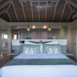 Luxurious bedroom interior with a high wooden ceiling, large bed, elegant lighting, and soft pastel decor in a villa rental.