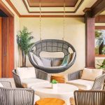 Luxurious villa interior with a hanging chair, comfortable seating area, and tropical plants.