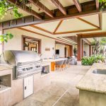 Luxurious outdoor kitchen and dining area with modern amenities, surrounded by lush greenery.