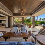 Luxury villa in Hawaii with an open patio, wooden furniture, and poolside view.