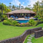 Luxury villa with a pool, surrounded by lush greenery and palm trees in Hawaii.