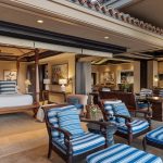 Luxurious Hawaiian villa with open-air living area featuring striped lounge chairs, a canopy bed, and elegant furnishings.