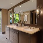 Luxurious bathroom with dual sinks, large mirror, and tropical garden view through a window.