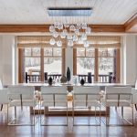 Ritz Carlton Bachelor Gulch WHRRZ Luxurious dining room with modern chandelier and snowy mountain view through large windows.