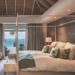 Luxury bedroom interior with ocean view, elegant decor, and a four-poster bed.